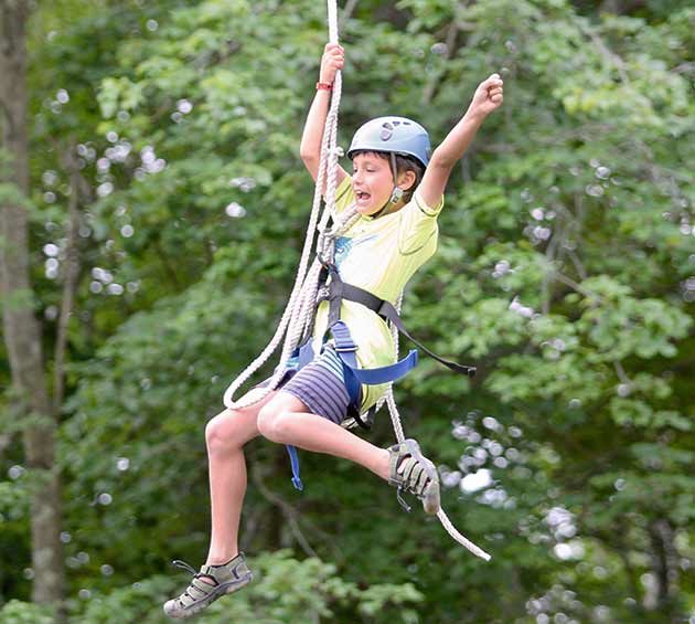 Boy rope swinging at Survival Camp.