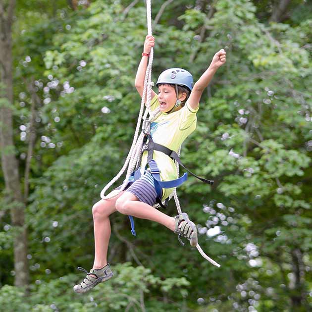 Boy rope swinging at Survival Camp.
