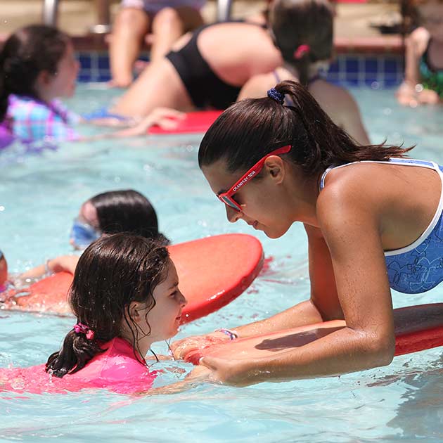 Safety Instructor teaching girl to swim at Jewish summer camp.