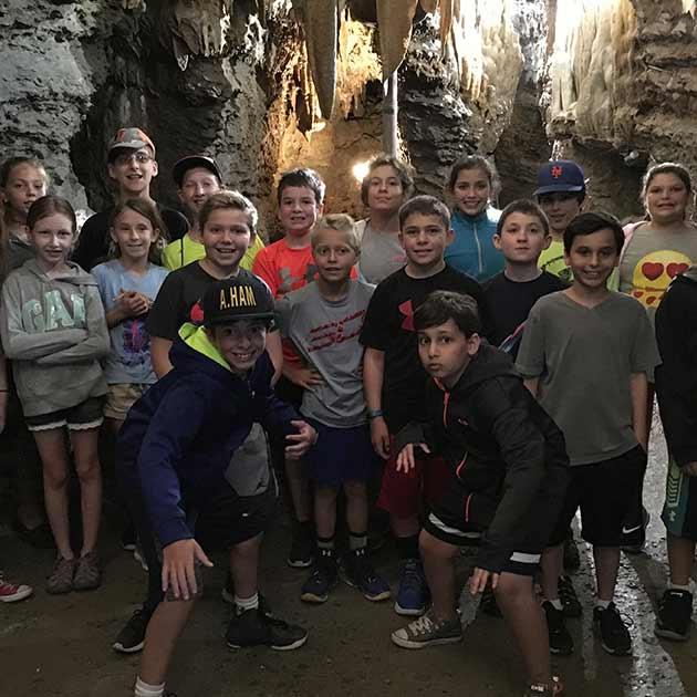 Group of kids smiling in a cave.